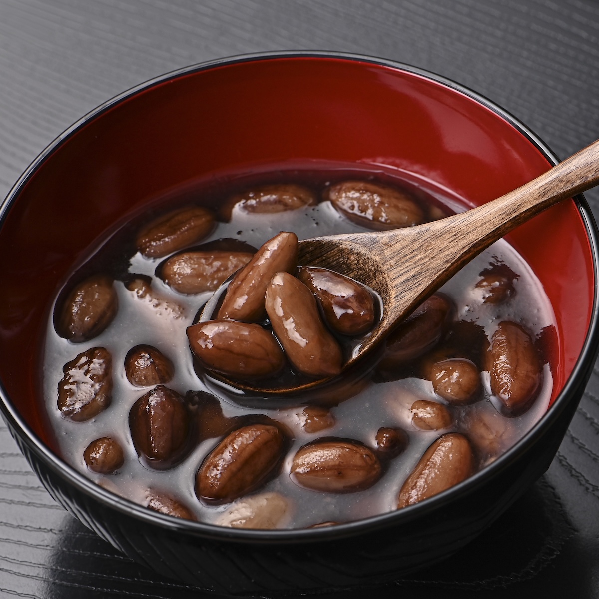 イメージの撮影実績：豆の艶や表面の質感、食べる場面が伝わるよう、黒と赤の器に盛り、木製スプーンですくう瞬間をアップで撮影しました。