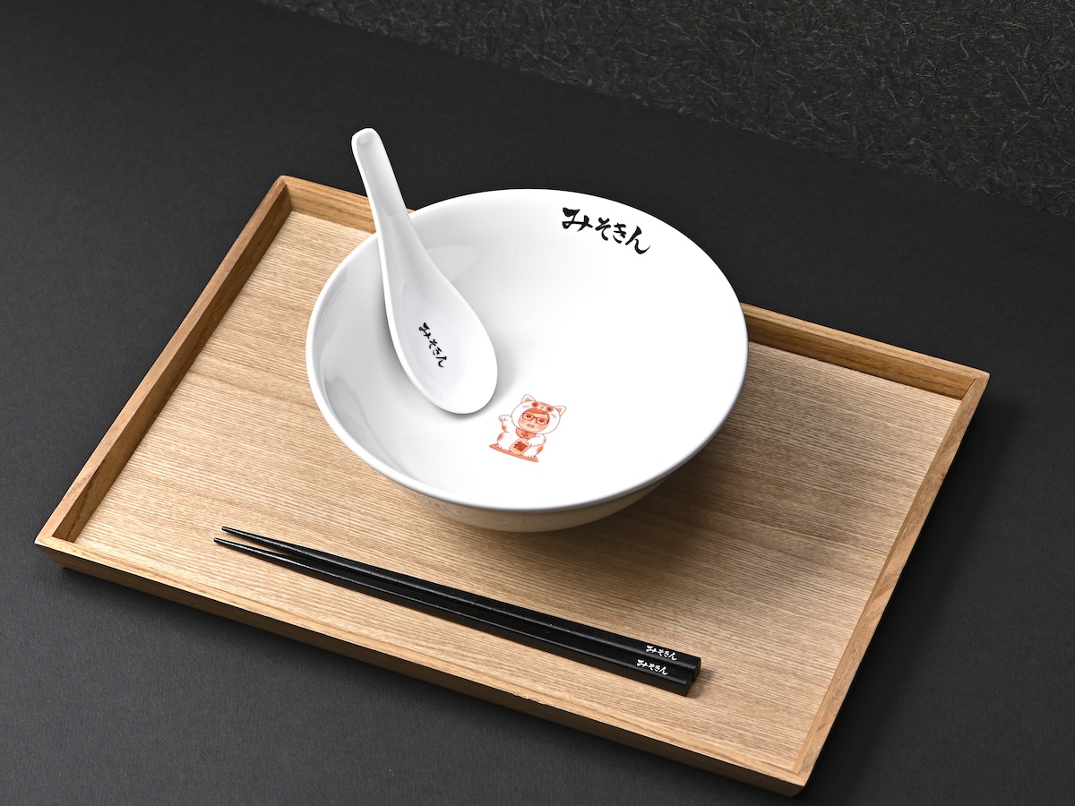 シチュエーションの撮影実績：ラーメンボウルとレンゲ、箸を木製トレーに整え、器の内側にある文字と底面の絵がクリアに見えるよう俯瞰気味に撮影しました。