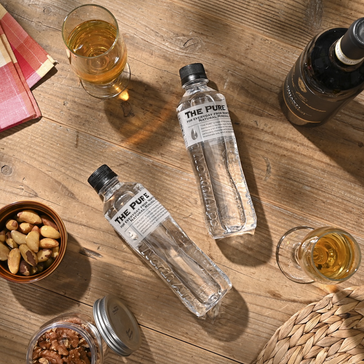 シチュエーションの撮影実績：水のボトル「THE PURE」を、ワインボトルを添えた高級感のある食卓シーンで撮影しました。