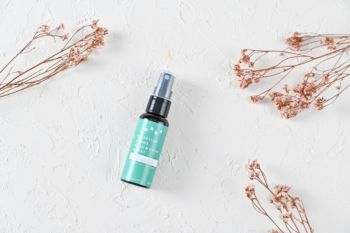 シチュエーションの撮影実績：PULSEYLEのAROMA MIST & ROOM SPRAYを白い壁の中央に置き、ターコイズ色のラベルとスプレーヘッドが正面から見やすいように撮影しました。