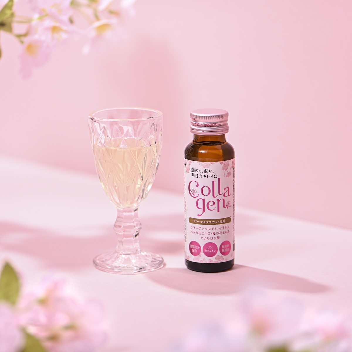シチュエーションの撮影実績：「Cola gem」と書かれたボトルを透明なグラスと並べ、ピンクの背景と桜の花で春の飲用シーンを表現しました。