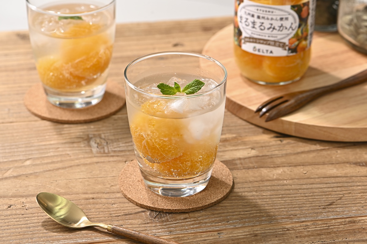 シチュエーションの撮影実績：丸ごとみかんの飲み物を透明なグラスに注ぎ、氷とミントを添えて、日常の食卓で楽しむイメージを撮影しました。