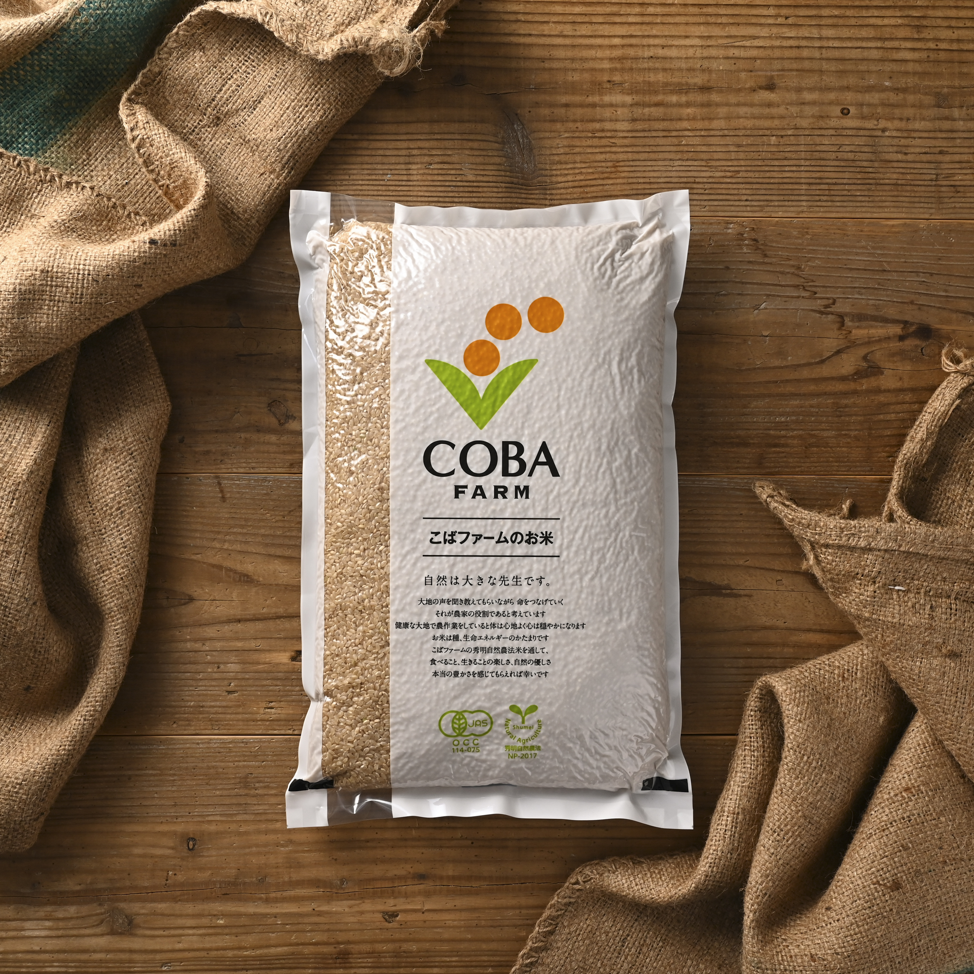 シチュエーションの撮影実績：COBA FARMの「こばファームのお米」を袋の正面が見えるように木のテーブルへ置き、商品名とロゴ、パッケージの形が確認しやすい俯瞰構図で撮影しました。