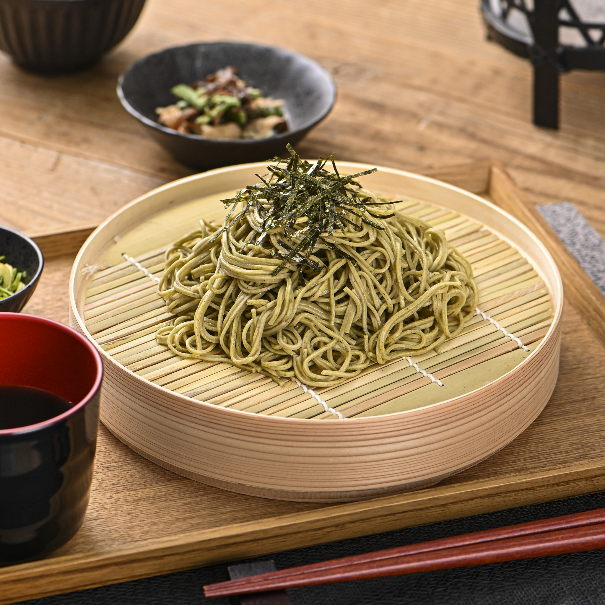 シチュエーションの撮影実績：緑色の抹茶そばを大きな竹ざるに縦型に盛り、刻みのりを中央に添えて、麺の色と一本ごとの立体感が伝わるように撮影しました。