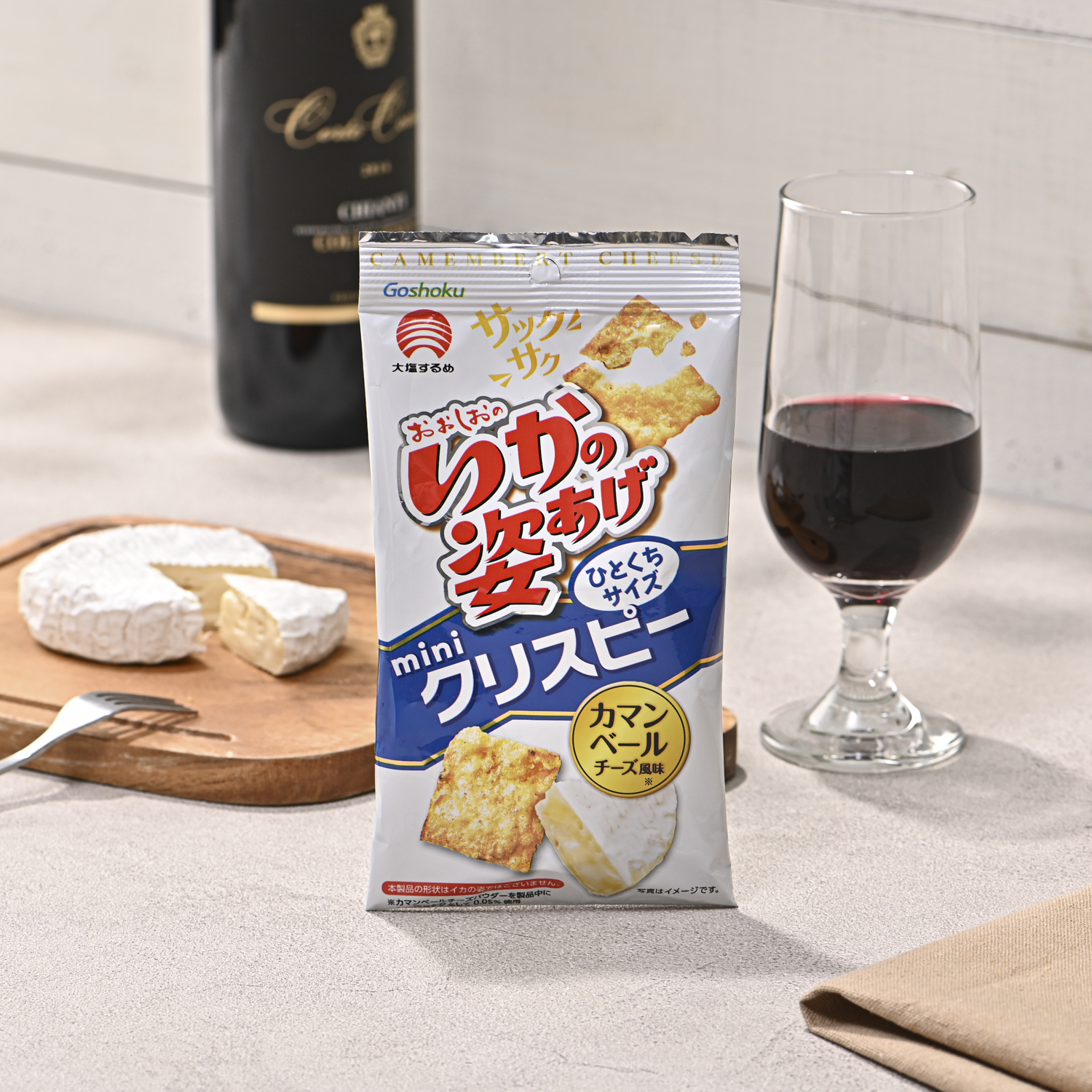 シチュエーションの撮影実績：チーズ風味のスナック菓子のパッケージを中央に立て、手前に商品とチーズ、背景に赤ワインを添えて撮影しました。