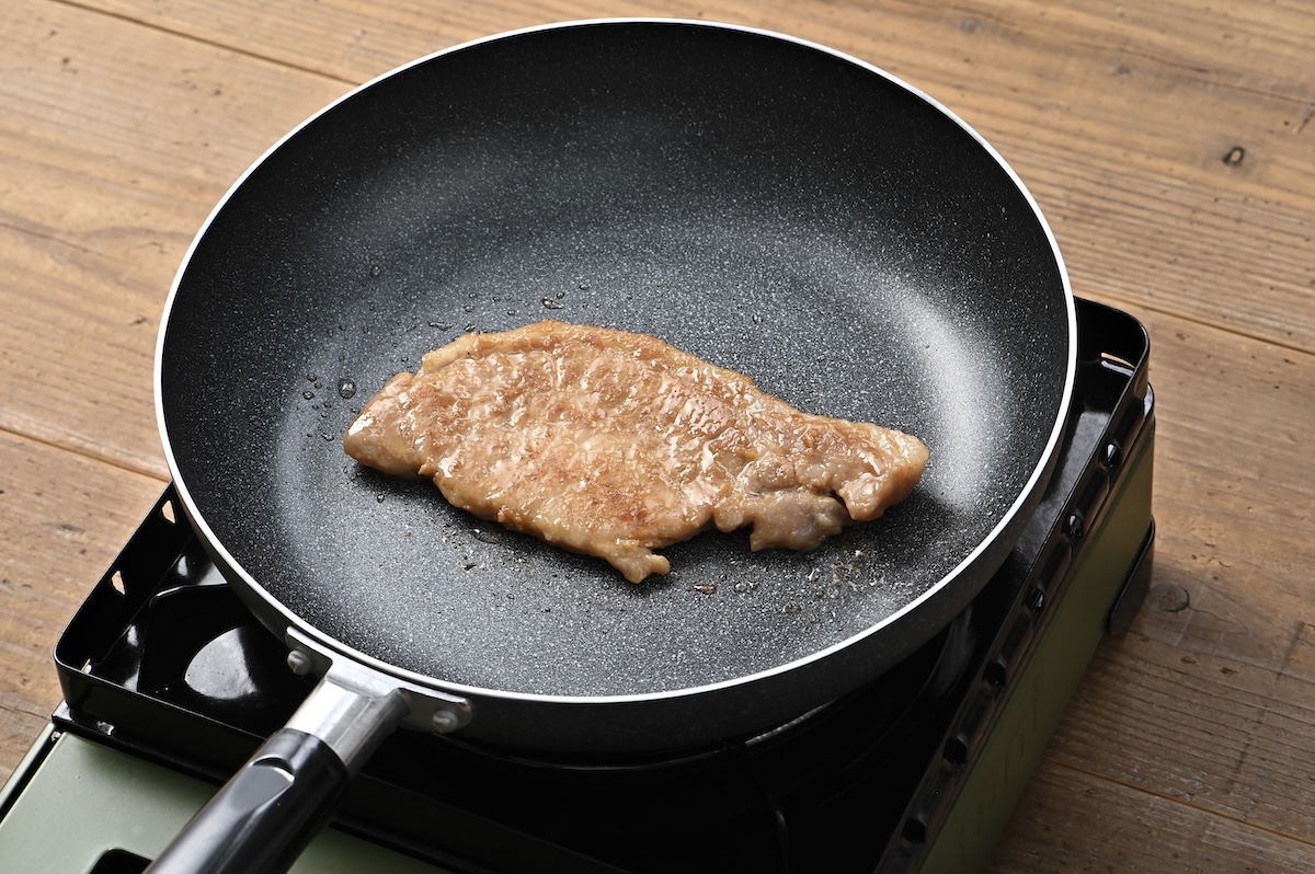 シチュエーションの撮影実績：豚肉をフライパンで焼く場面を上から捉え、LPの調理手順に使いやすいシチュエーション写真に仕上げました。